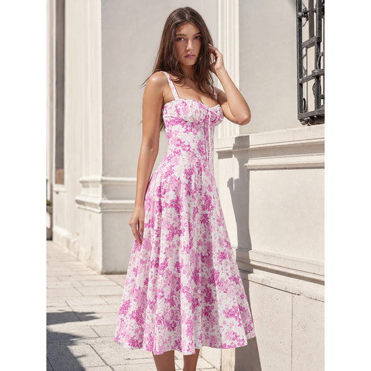 Women’s midi dress with thin straps and a square neckline, featuring a front tie, visible pleats at the bodice, and a floral print on a white background with pink-red flowers. The waist-defined, flared-skirt silhouette creates a recognizabl