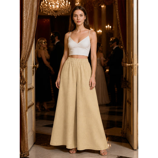 Beige wide-leg pants shown full-length on a model with an elastic waistband and flowing legs in a formal interior