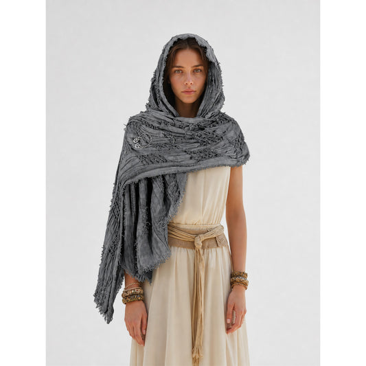 This large scarf-wrap is designed as a rectangular drape with a striking textured surface. The black-and-gray color palette is accented with lighter gray tones, giving the piece a distinctive look that pairs easily with different outfits. T