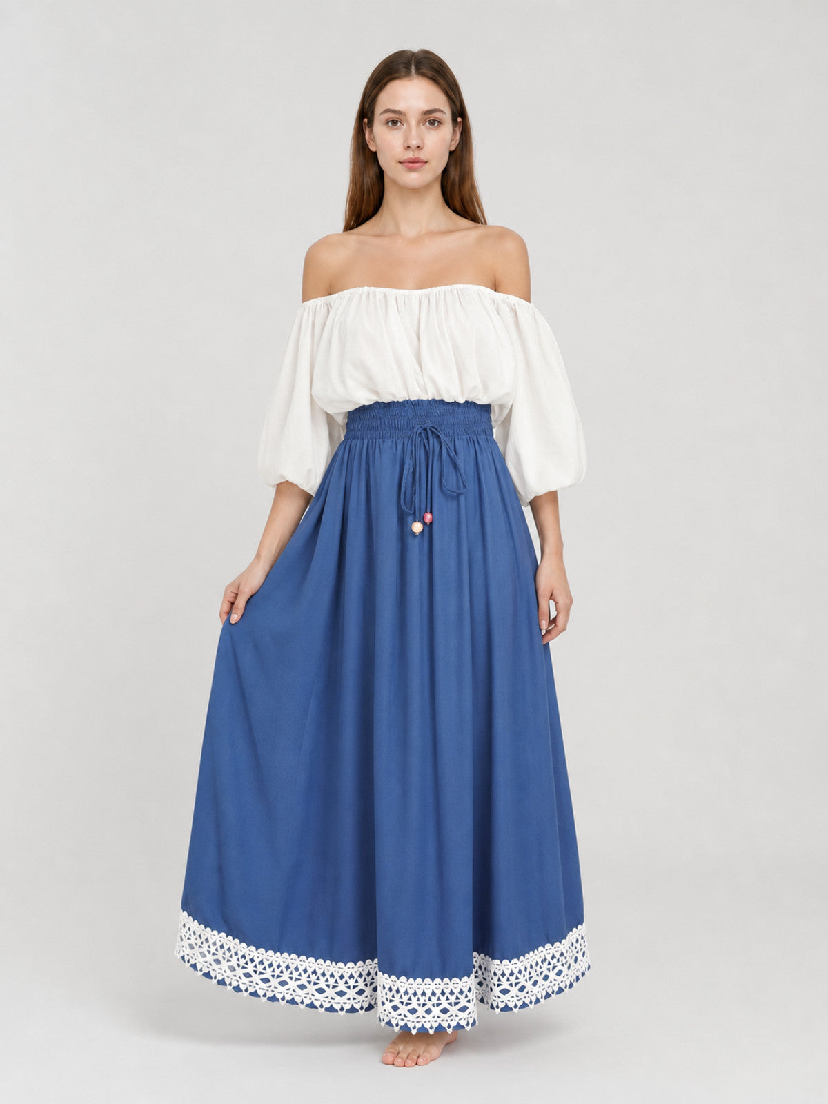 Front full-body view of a blue maxi dress with a white off-shoulder gathered top, puff sleeves, and white lace hem