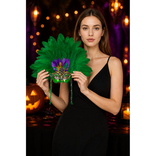 Green feather eye mask with purple and gold embellishments held by a woman in a black dress at a Halloween-themed table