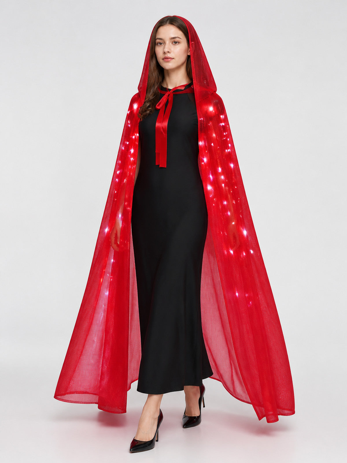 Full-body model wearing a sheer red hooded cape with glowing lights along the sides and a front tie