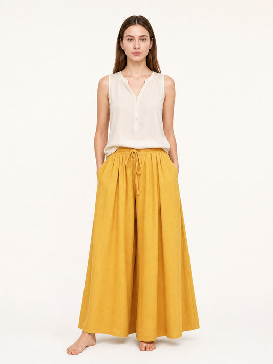 Wide-leg mustard yellow pants on a full-body model, with a high gathered waist, front drawstring, and flowing fabric