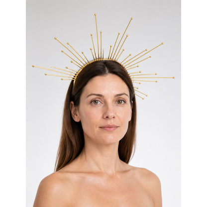 Gold-tone metal halo headpiece with radiating slender rays and ball tips, shown front-facing on a model against a gray background