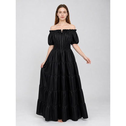 Front view of a black off-shoulder maxi dress on a model holding the skirt, showing puff sleeves, a fitted waist, and multiple gathered tiers