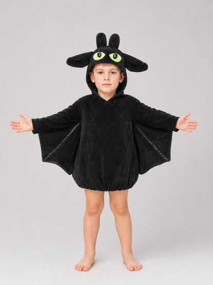 Black plush bat costume shown full-body on a child, with hood, upright ears, large eyes, and outstretched wing panels