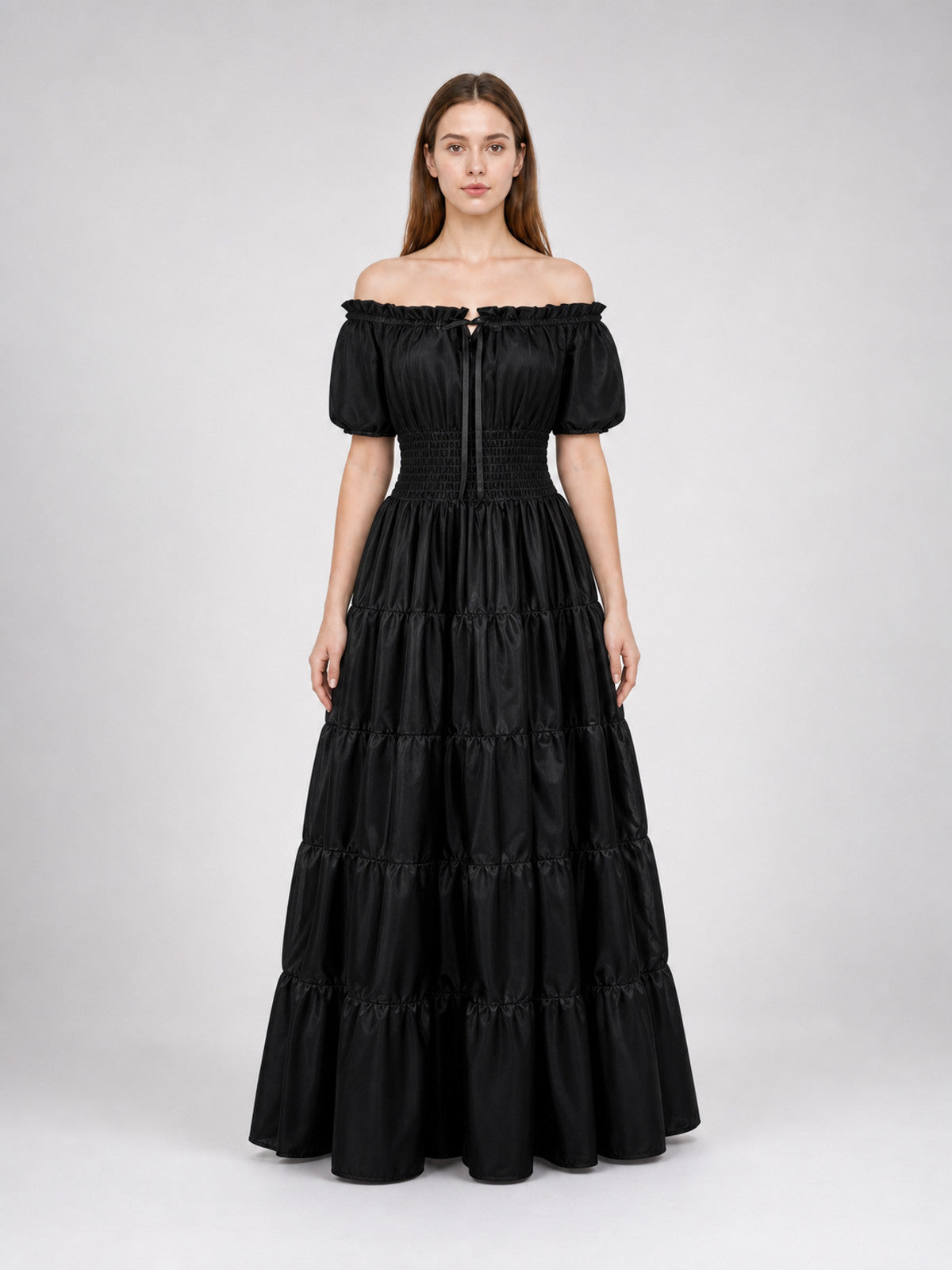Black maxi dress on a full-body model, with an off-shoulder neckline, short puff sleeves, fitted waist, and multiple gathered skirt tiers