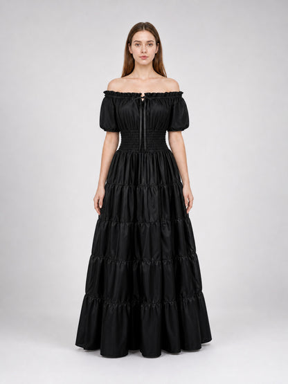 Black maxi dress on a full-body model, with an off-shoulder neckline, short puff sleeves, fitted waist, and multiple gathered skirt tiers