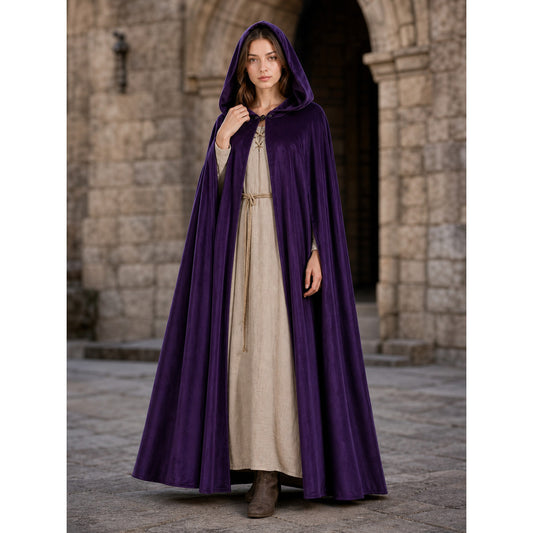 Purple hooded cape shown full-body on a model in a stone courtyard, with a floor-length drape and front clasp