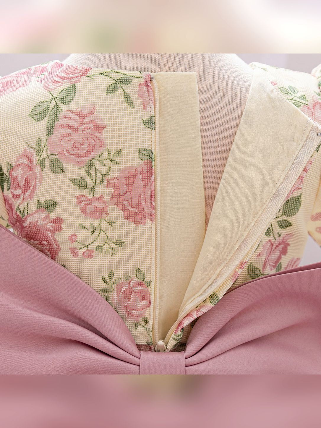 Close-up of the back zipper and dusty-pink bow on the baby girls' floral princess dress