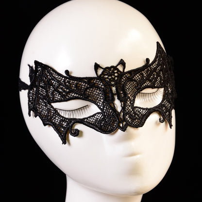 Close-up of the black lace bat eye mask showing openwork mesh lace, curled edges and the small bat motif at the center