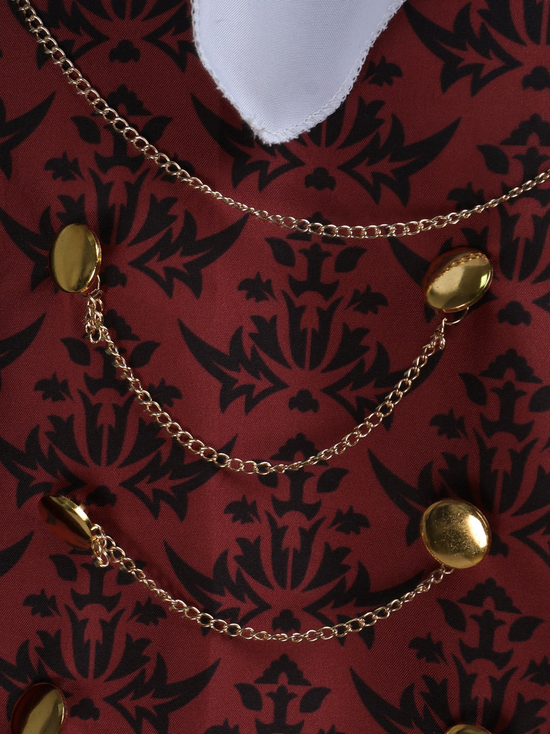 Close-up of the red damask vest fabric with gold-tone buttons and draped gold chains