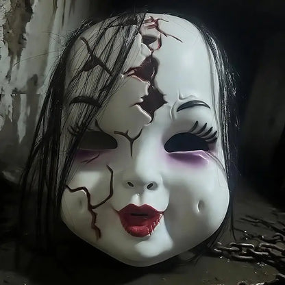Close-up of the cracked doll mask showing red cracks, painted lashes and red lips