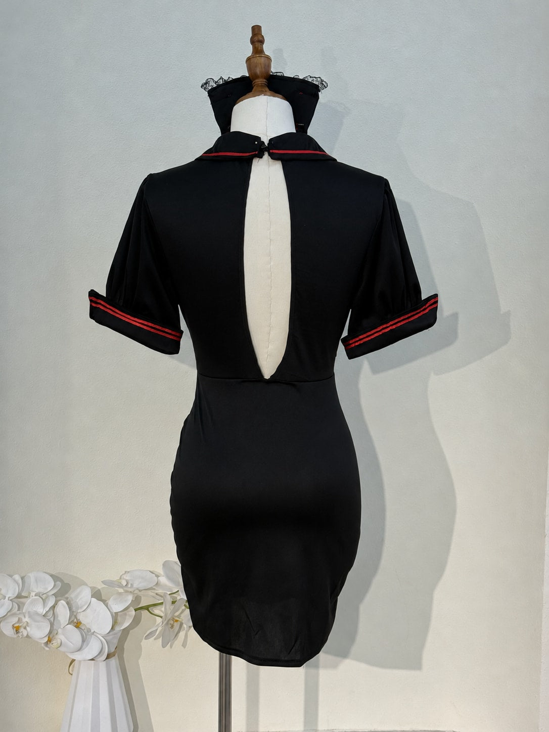 Back view of the black nurse cosplay dress showing the open keyhole back and red-striped cuffs