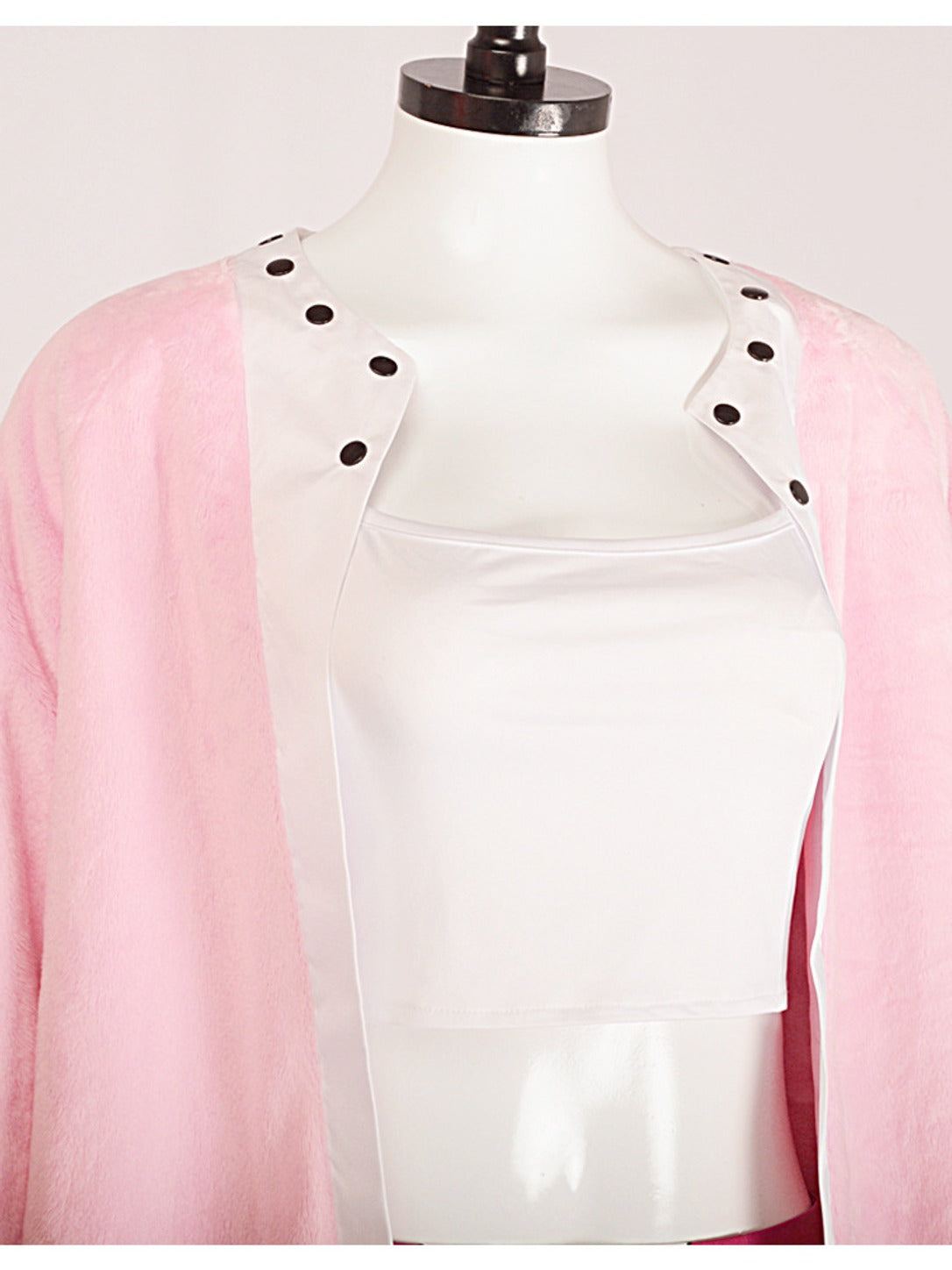 Close-up of the pink jacket's white lapels with black round studs over the white cropped camisole