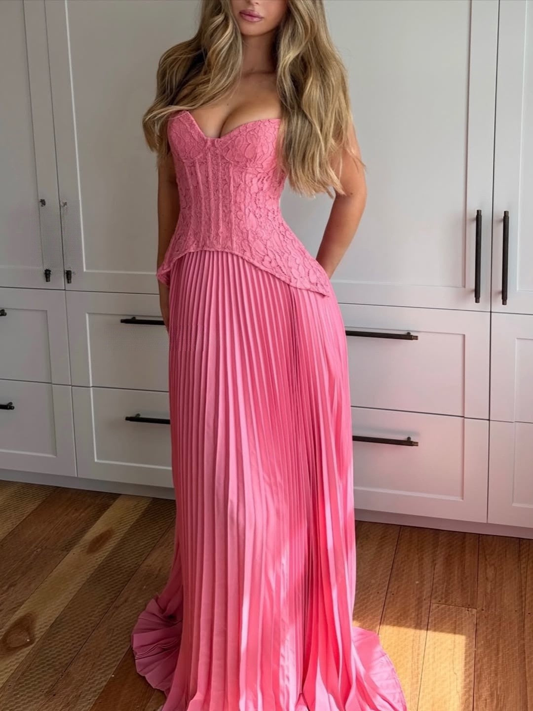 Pink corset maxi dress with lace bodice and pleated skirt worn indoors, front view