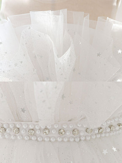 Close-up details of the girls' princess dress: ruffled star-print tulle neckline and faux pearl and rhinestone waistband