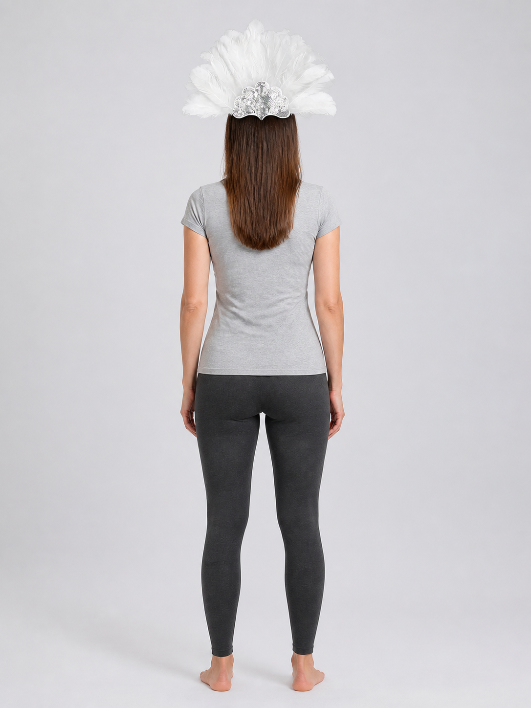 Rear view of a model wearing the white feather headband, showing the feather fan above her gray shirt