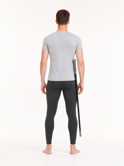 Back view of a man in a gray shirt and dark leggings holding the black cane beside his right leg
