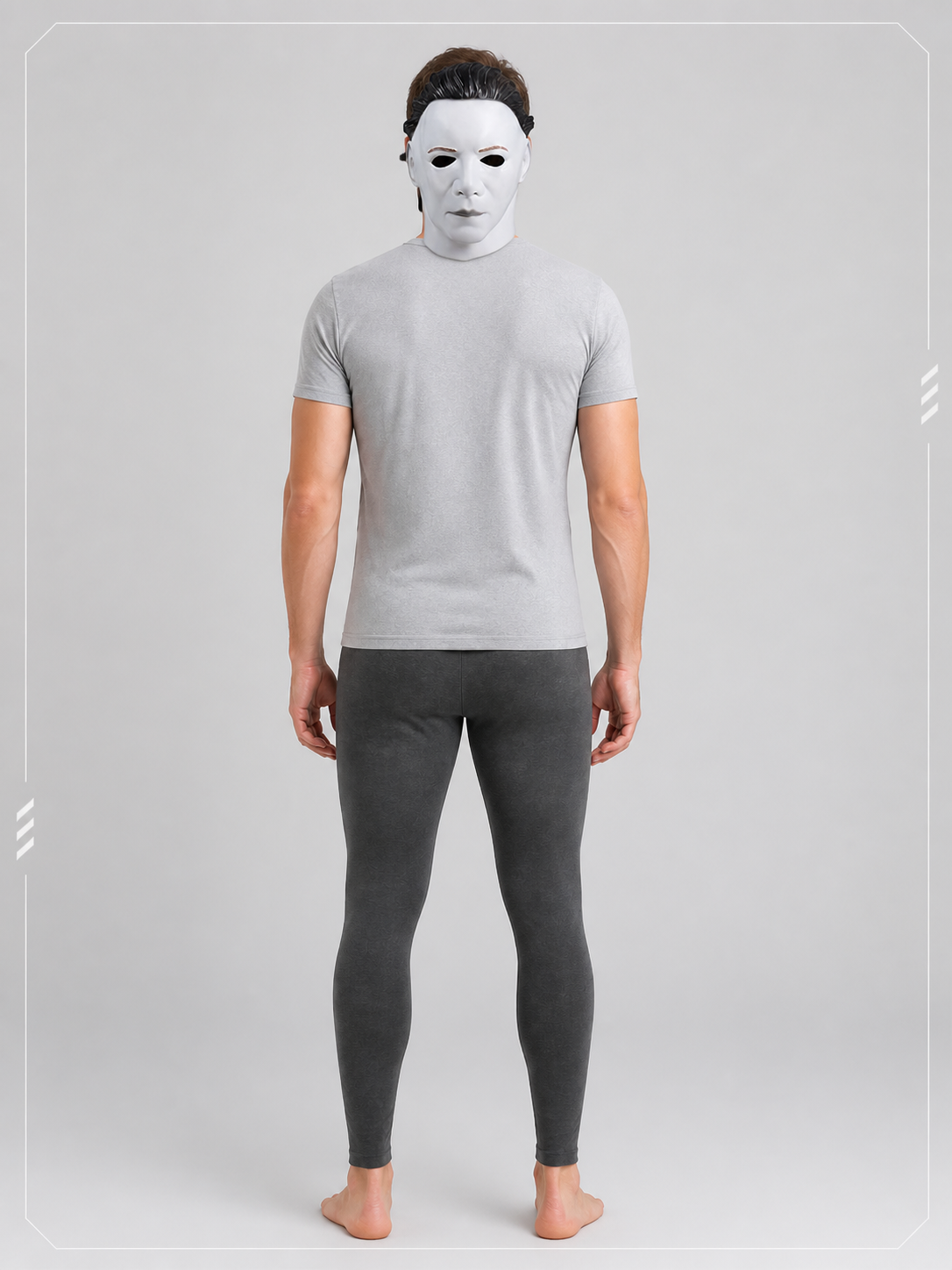 Full-body rear view of a person wearing the white face mask, gray shirt, and dark leggings against a plain gray background