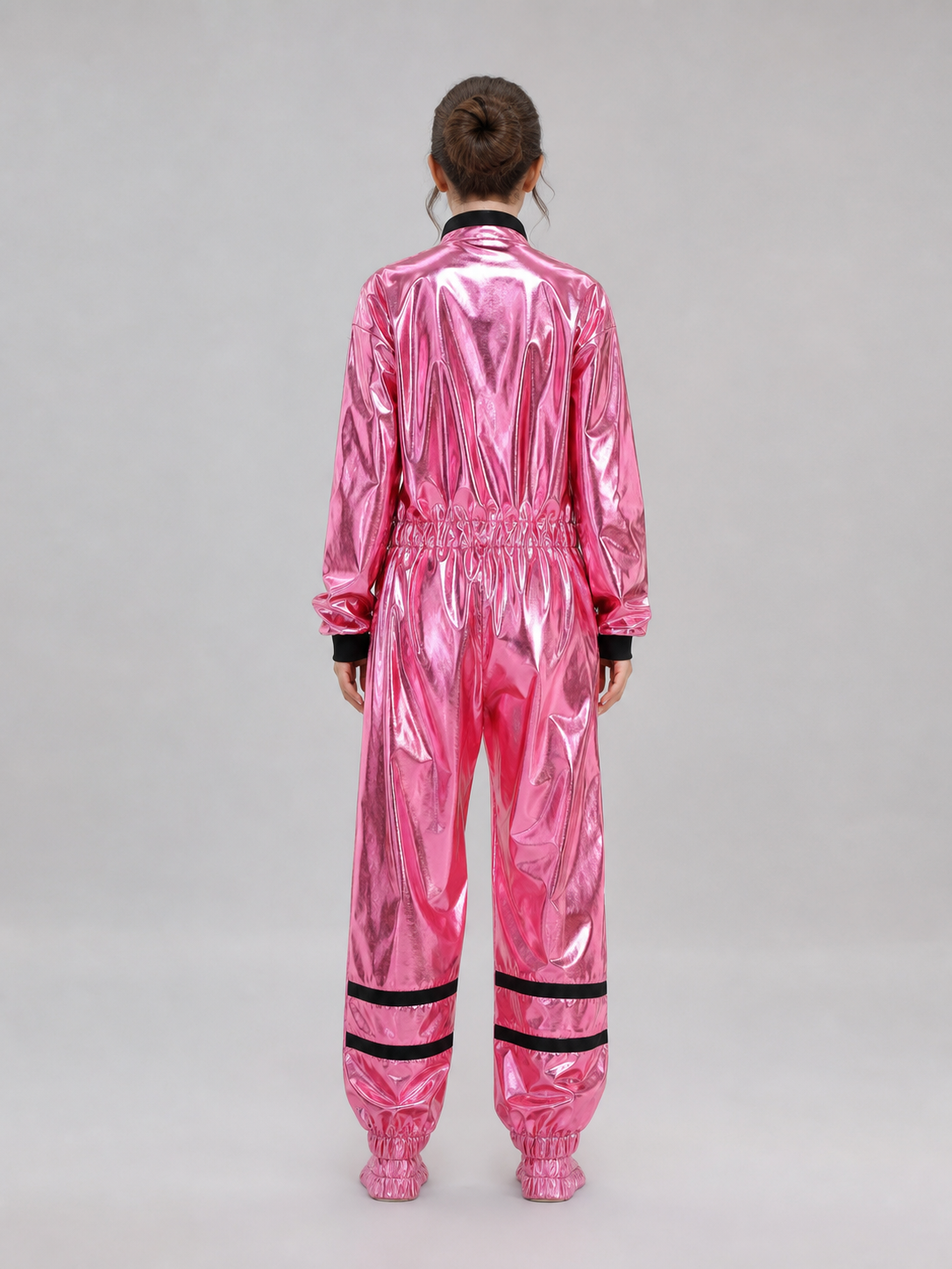 The pink NASA astronaut costume is designed as a one-piece jumpsuit with long sleeves, a stand-up collar, and a central zip closure. The model is pink with black decorative elements: a vertical stripe on the front, zippered side pockets, ho