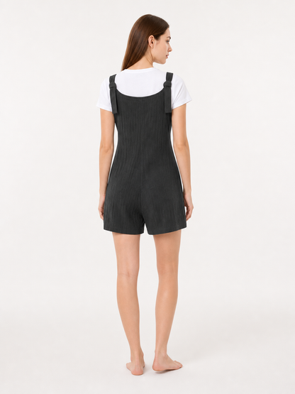 Back view of black textured bib shorts with shoulder straps, shown on a model wearing a white T-shirt