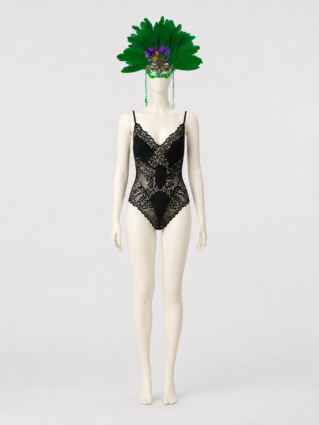 Full-body mannequin wearing the green feather mask with long side strands and a black lace bodysuit against a gray background
