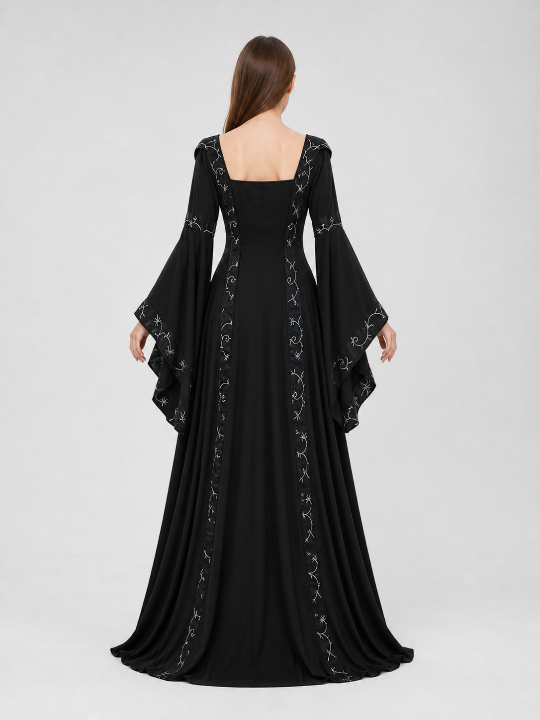 The dress is designed in a gothic style with elements of Victorian aesthetics. The model features a flared silhouette, a square neckline, and long sleeves with flared cuffs. The bodice is decorated with gathers that emphasize the garment’s 