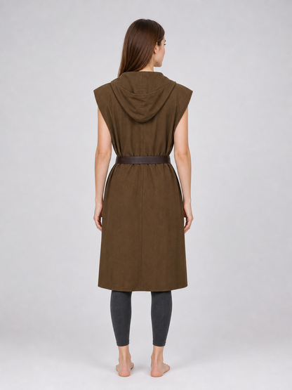 Back view of a brown sleeveless hooded vest with a dark waist belt on a female model wearing dark leggings