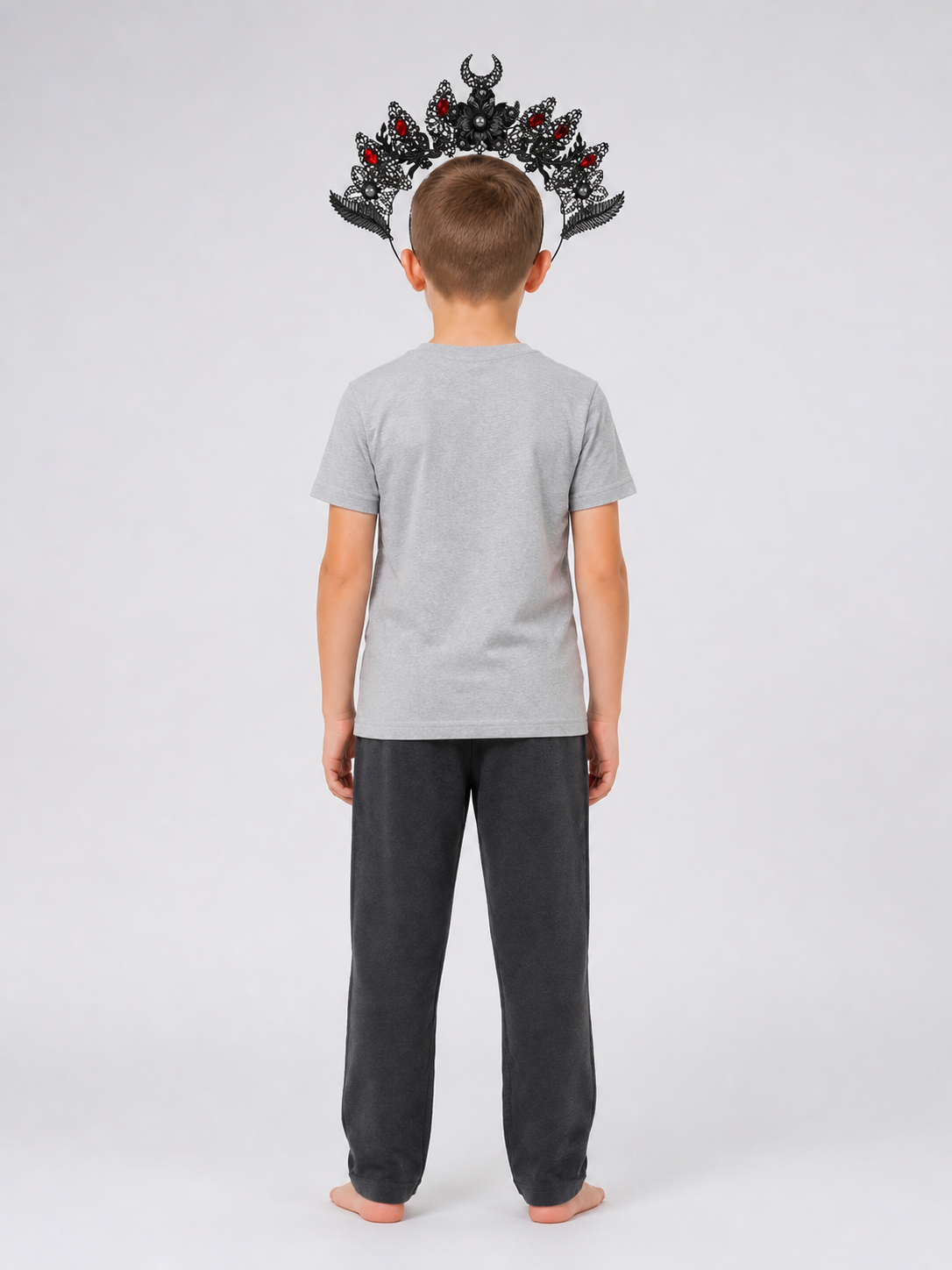 Black and silver-look horned headpiece with red stones and filigree details, shown from the back on a child wearing a gray shirt
