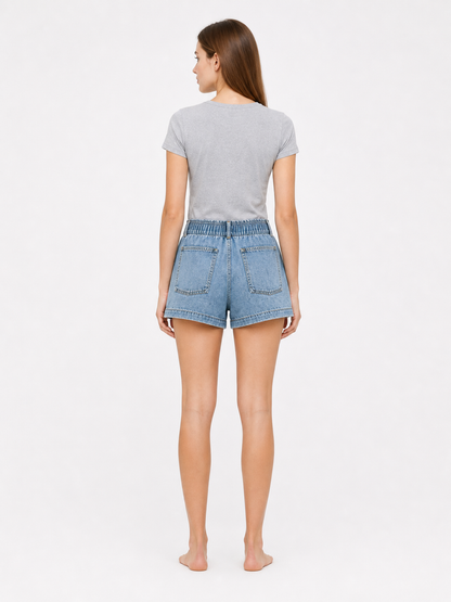 Light blue denim shorts shown from the back on a model, with two rear patch pockets and an elastic waistband