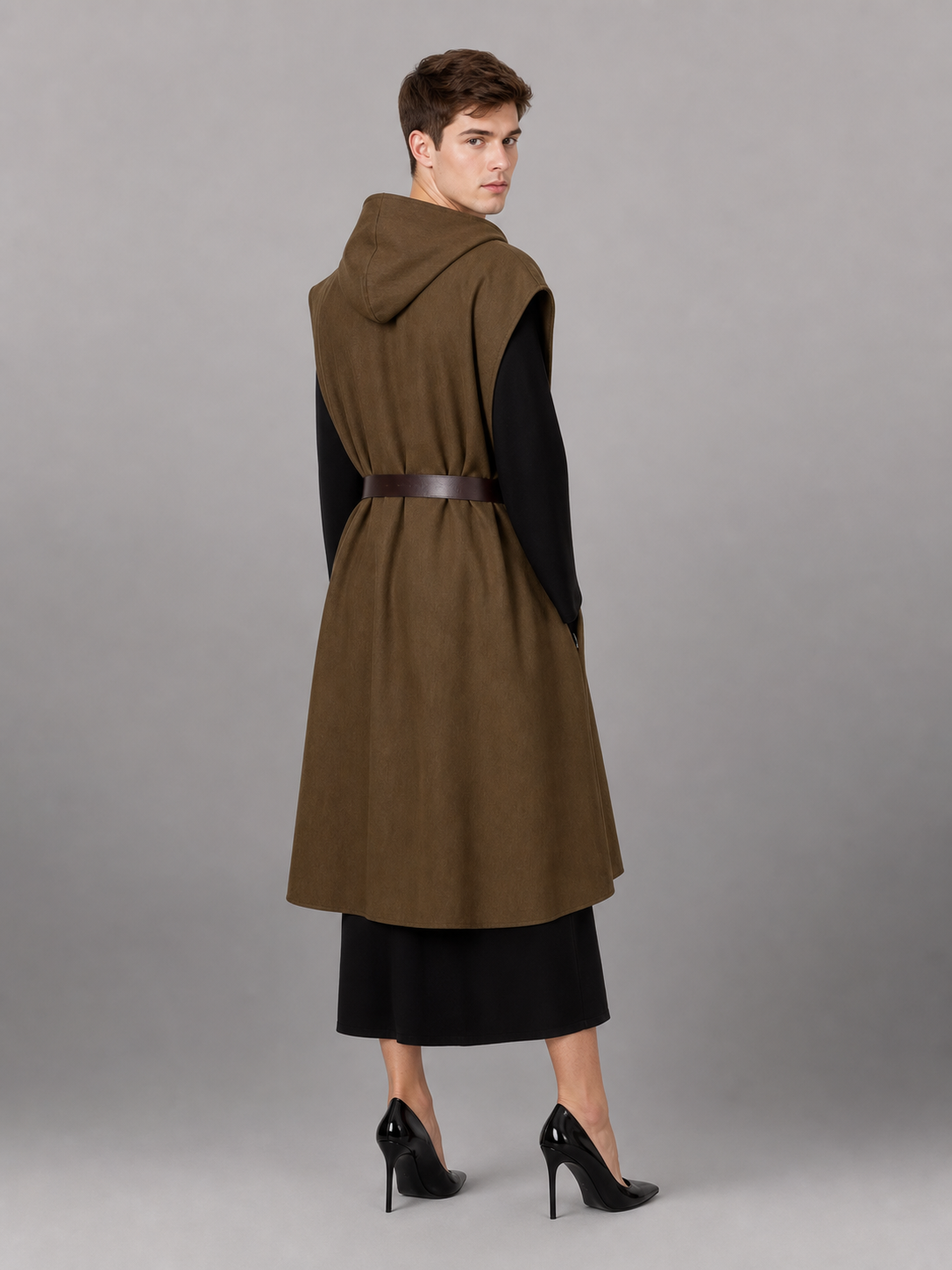 Back view of a brown hooded vest with a dark belt on a male model wearing a black outfit and black high heels