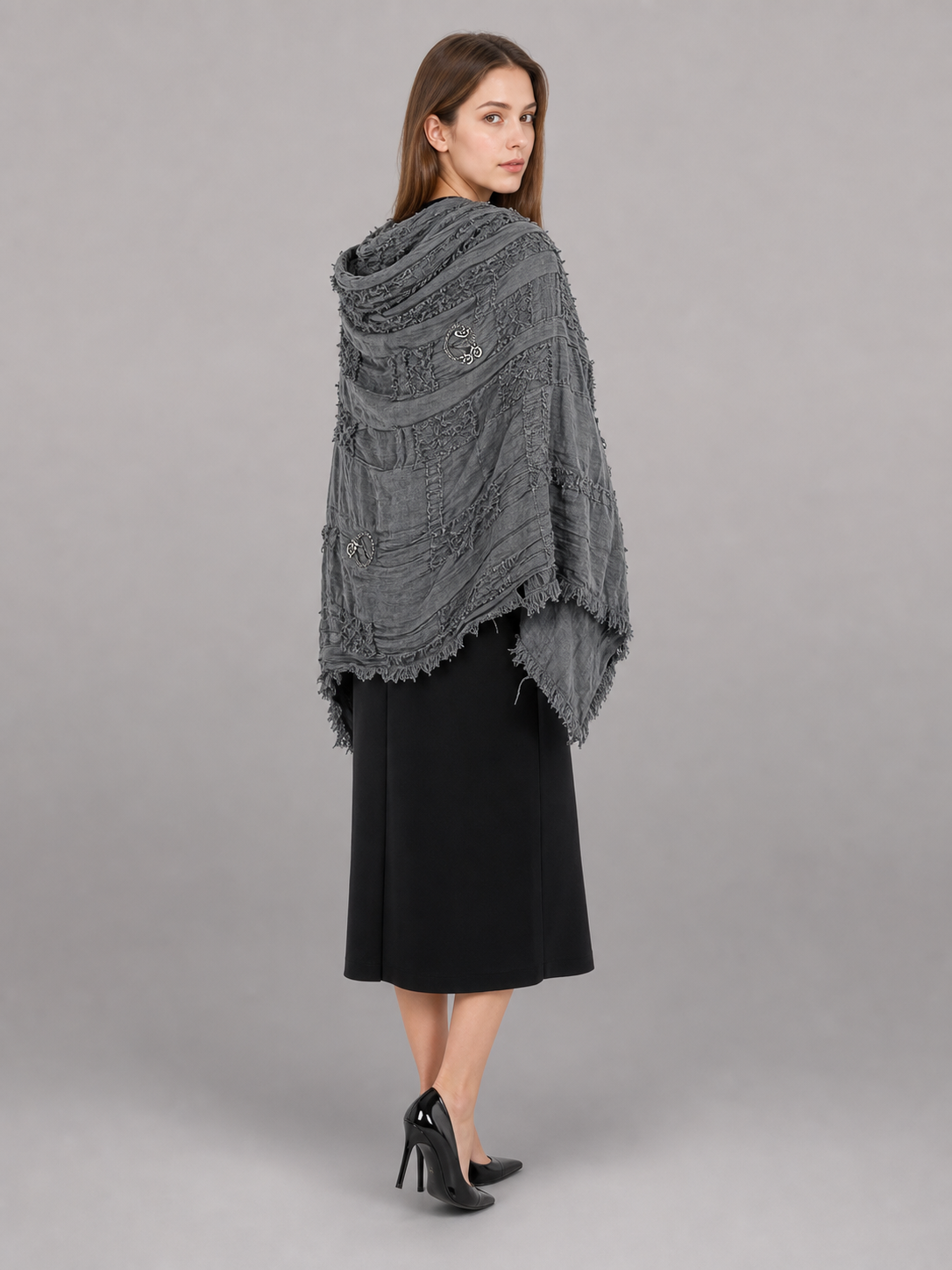 This large scarf-wrap is designed as a rectangular drape with a striking textured surface. The black-and-gray color palette is accented with lighter gray tones, giving the piece a distinctive look that pairs easily with different outfits. T