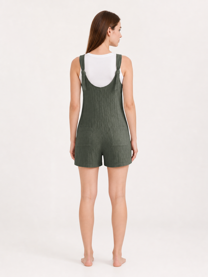 Back view of olive green textured overall shorts worn over a white T-shirt, showing the tied shoulder straps and loose short-leg silhouette