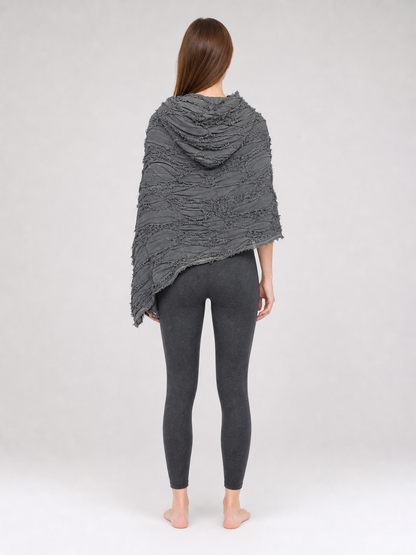 This large scarf-wrap is designed as a rectangular drape with a striking textured surface. The black-and-gray color palette is accented with lighter gray tones, giving the piece a distinctive look that pairs easily with different outfits. T
