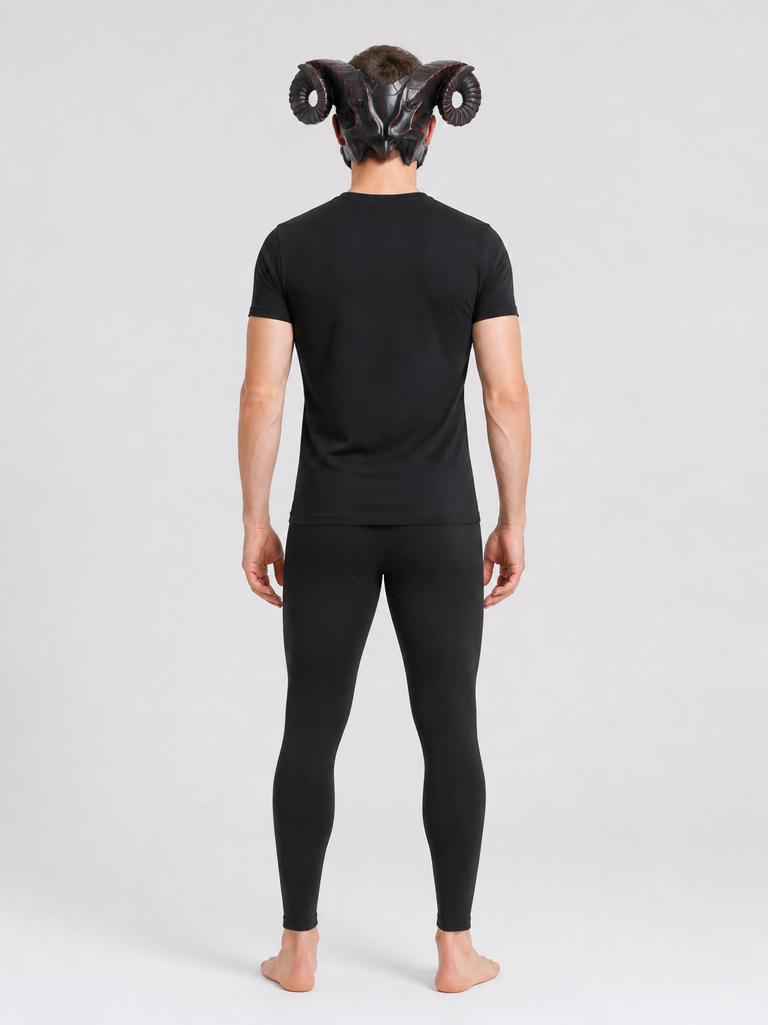 Full-body rear view of a man wearing the horned mask with curled ridged horns, a black shirt, and dark leggings