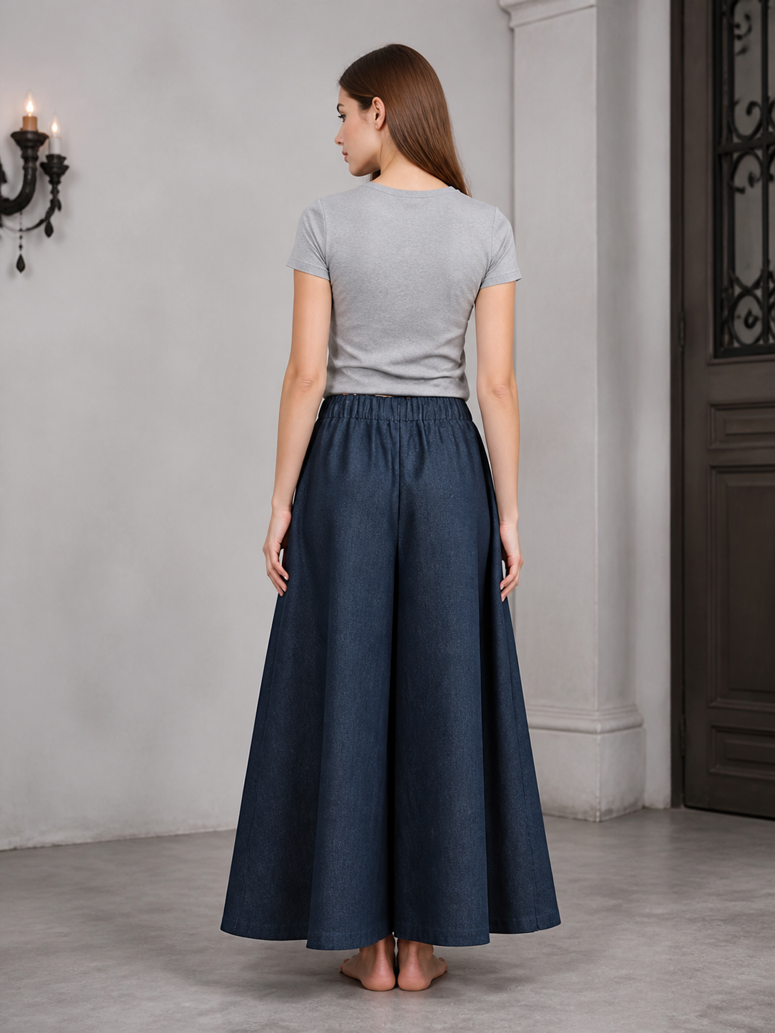 Back view of dark blue wide leg pants with an elastic waistband, shown on a model wearing a gray T-shirt