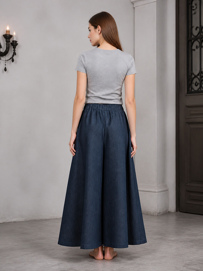 Back view of dark blue wide leg pants with an elastic waistband, shown on a model wearing a gray T-shirt