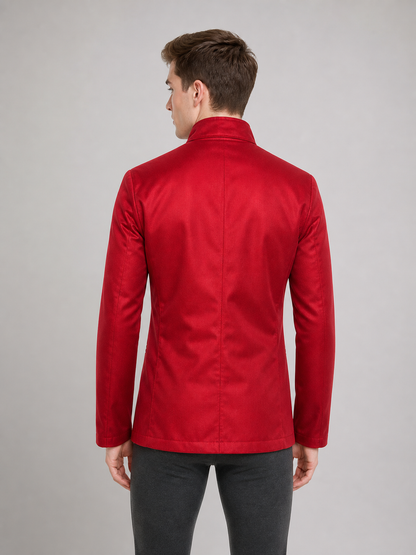 The jacket is presented in a vintage red color and designed in a military style with elements of Gothic aesthetics. The model features a distinctive front construction with a diagonal wrap, giving the garment a bold character. A double row 