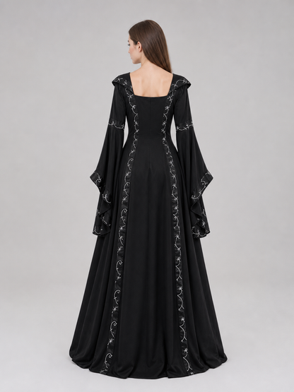 The dress is designed in a gothic style with elements of Victorian aesthetics. The model features a flared silhouette, a square neckline, and long sleeves with flared cuffs. The bodice is decorated with gathers that emphasize the garment’s 