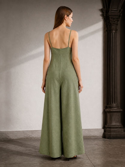 Back view of an olive green wide-leg jumpsuit with thin straps and wide legs, shown on a model in an indoor archway
