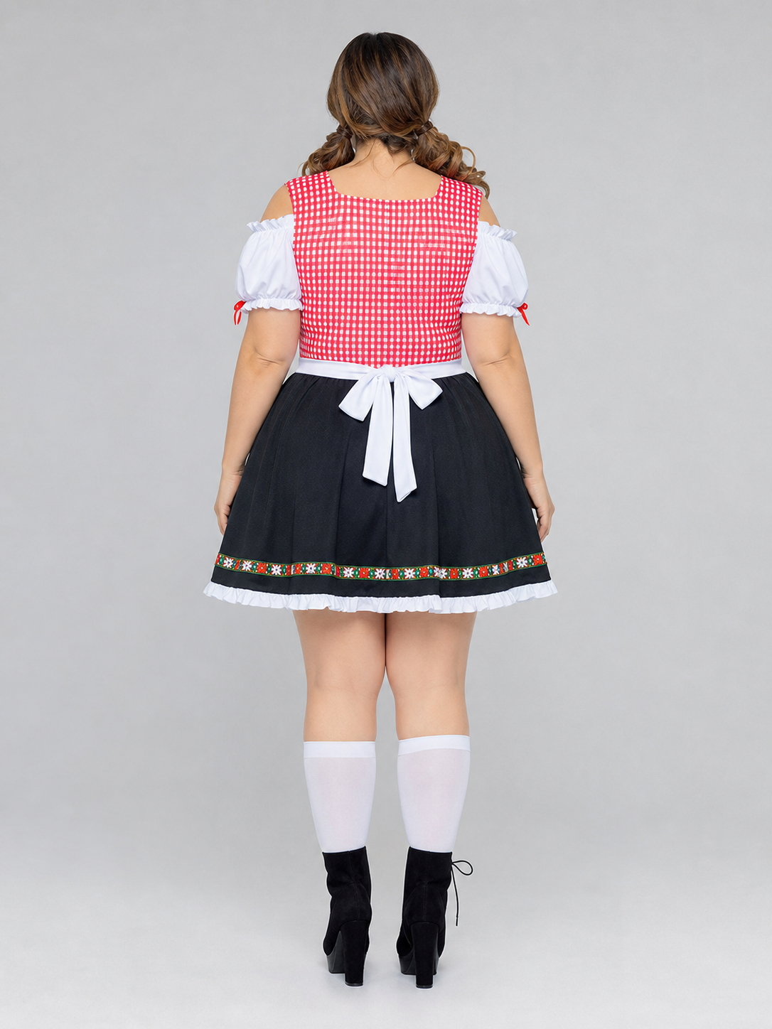 Historical national costume presented as a dress-like outfit with a decorative apron and distinctive details. The design combines white, red, and black colors: the top features a red-and-white checkered pattern, while the lower part is desi