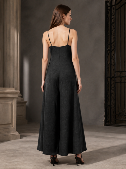 Back view of a black wide-leg jumpsuit with thin straps, shown on a model wearing black heeled sandals indoors