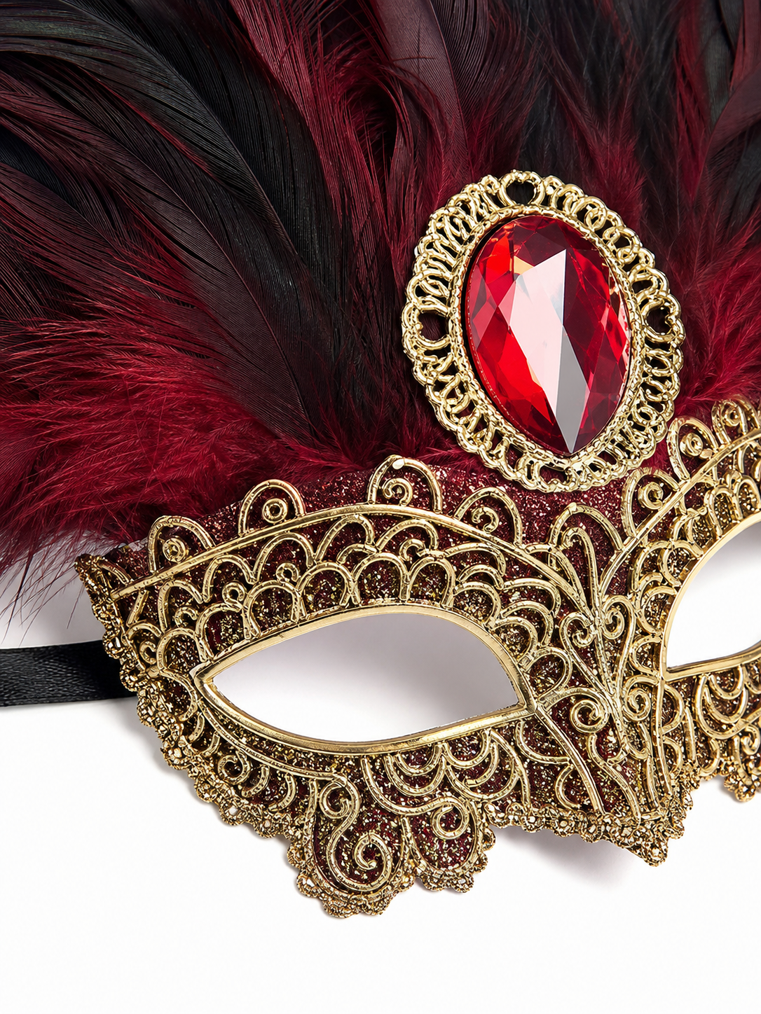 Close-up of gold filigree mask detailing, red oval jewel, and layered burgundy and black feathers