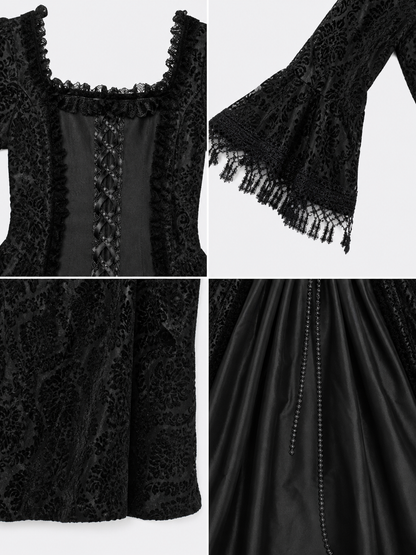 The black dress is designed in the aesthetic of a Victorian-era Gothic costume. The model features a floor-length silhouette, a fitted bodice with a square neckline, and decorative lacing or trim on the front. The long flared sleeves end in