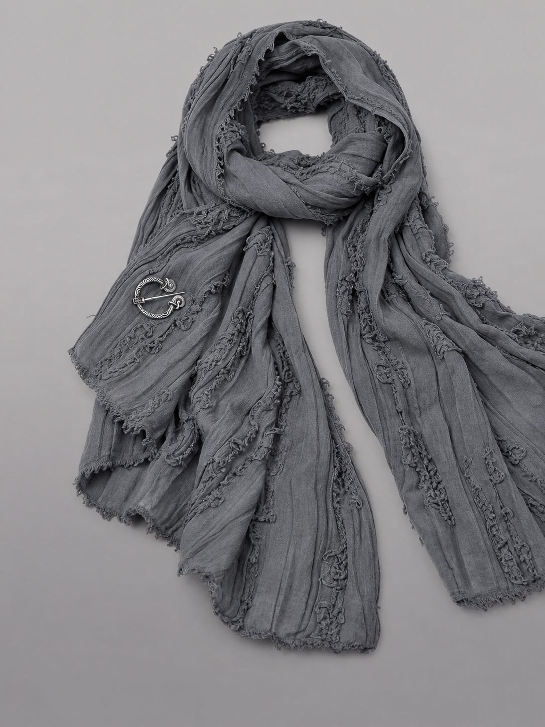 This large scarf-wrap is designed as a rectangular drape with a striking textured surface. The black-and-gray color palette is accented with lighter gray tones, giving the piece a distinctive look that pairs easily with different outfits. T