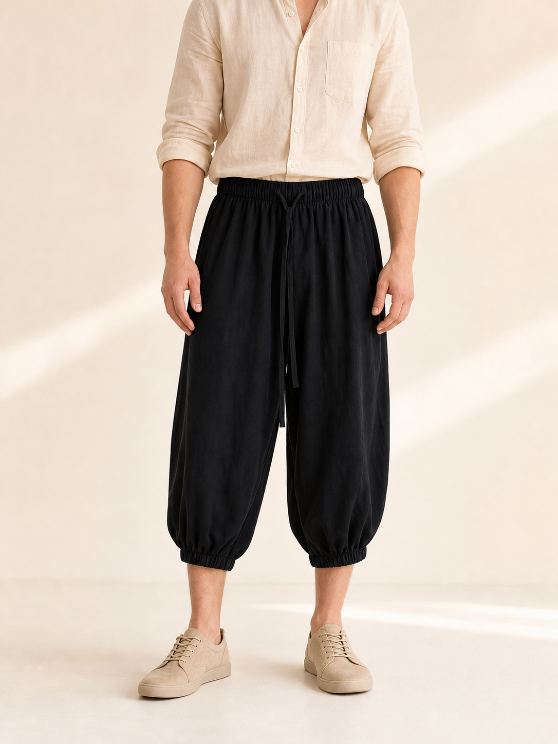 Black cropped pants shown from the waist to the ankles on a model, paired with a light shirt and beige sneakers
