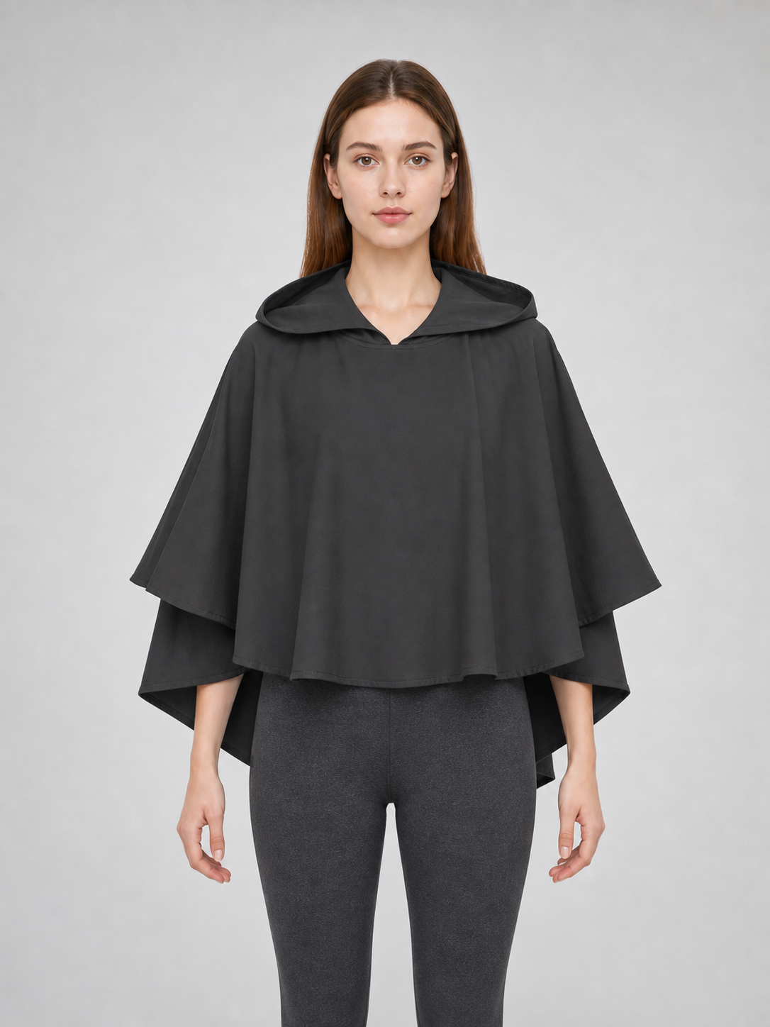 Dark gray hooded poncho with wide sleeves and layered edges, shown on a female model from the front