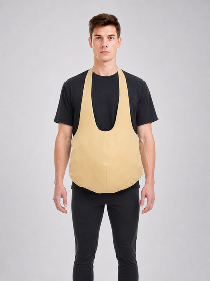 Wearable fake belly costume accessory with a large rounded shape. The model has a bib-style front panel, two shoulder straps, and side ties for fastening. The smooth solid-color surface comes in a light beige or beige shade, so the accessor