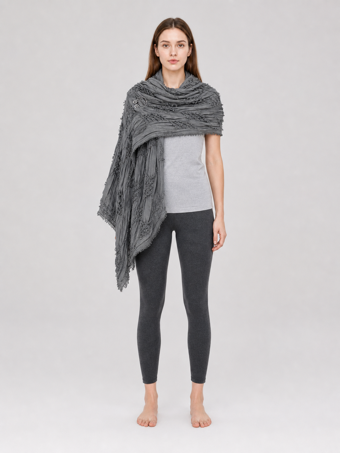 This large scarf-wrap is designed as a rectangular drape with a striking textured surface. The black-and-gray color palette is accented with lighter gray tones, giving the piece a distinctive look that pairs easily with different outfits. T